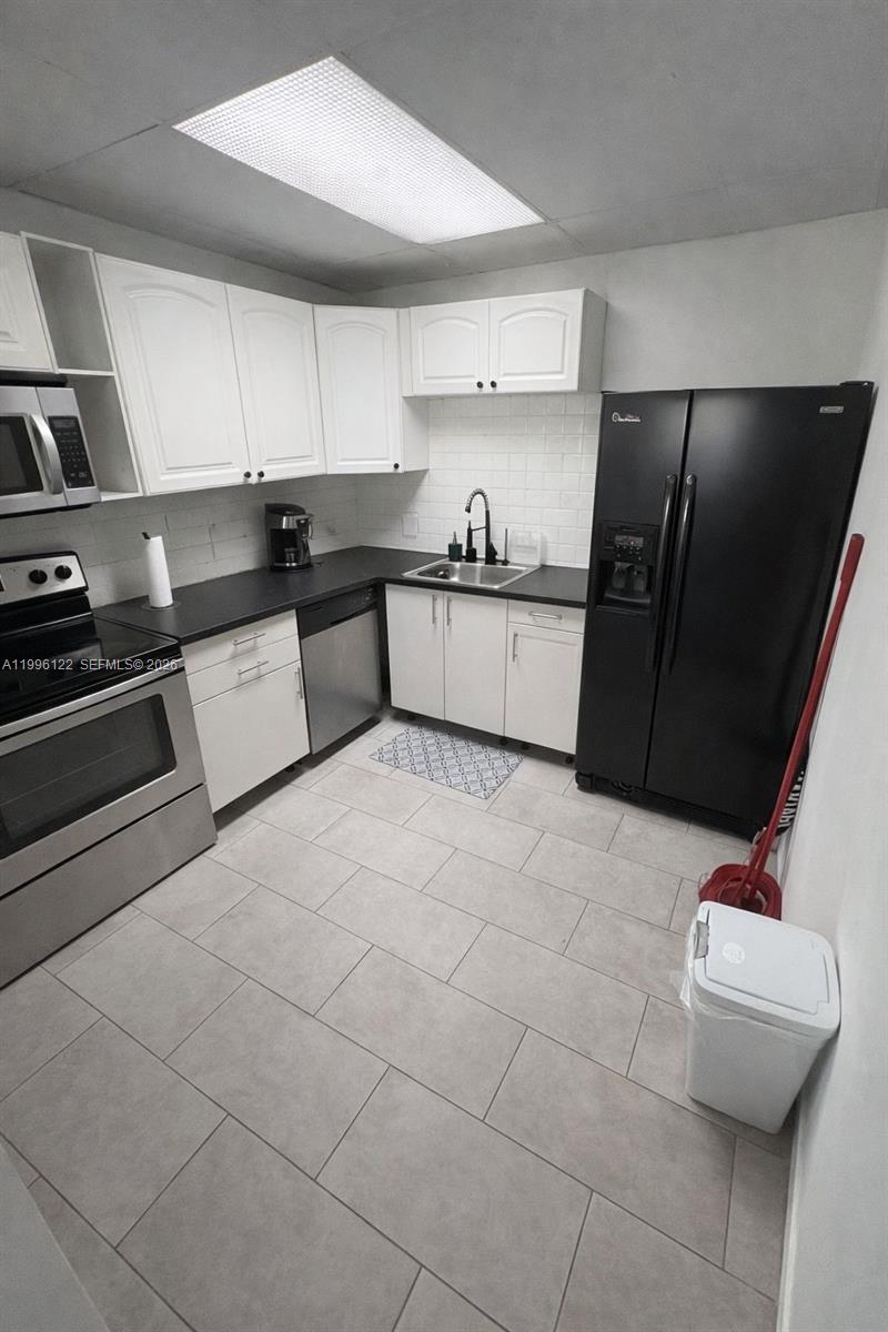 1220 71st Street, Unit 38 Miami Beach, FL 33141 - Photo 7 of 22 a kitchen with stainless steel appliances a refrigerator sink and cabinets