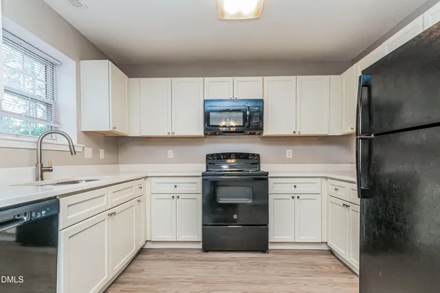 a kitchen with a sink white cabinets and stainless steel appliances