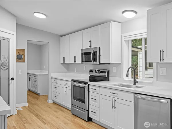 a kitchen with white cabinets and appliances
