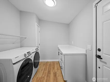 a view of a kitchen with stainless steel appliances granite countertop a stove top oven a sink dishwasher and white cabinets with wooden floor