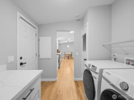 a large white kitchen with kitchen island a sink dishwasher a stove and white cabinets with wooden floor