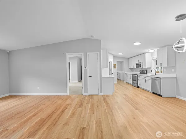 a large white kitchen with kitchen island a sink dishwasher a stove and white cabinets with wooden floor