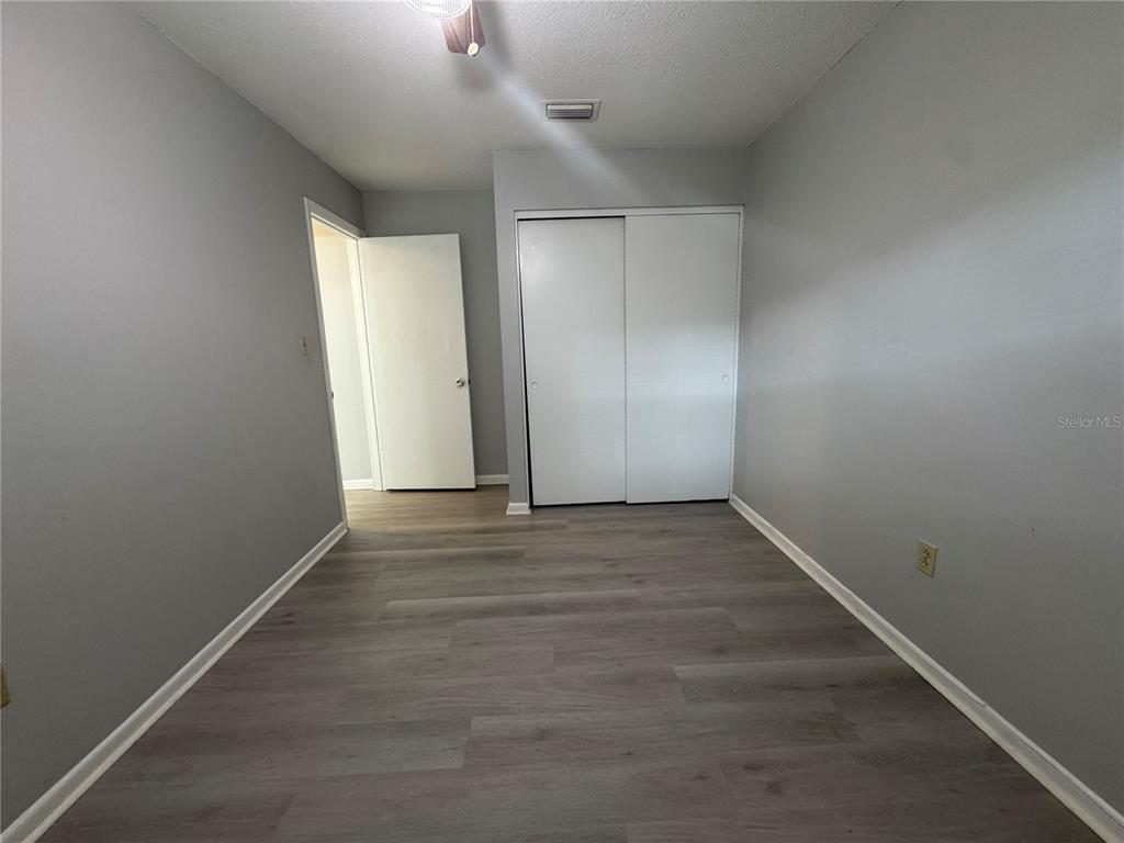 1610 High Street Leesburg, FL 34748 - Photo 8 of 11 an empty room with wooden floor cabinet and windows