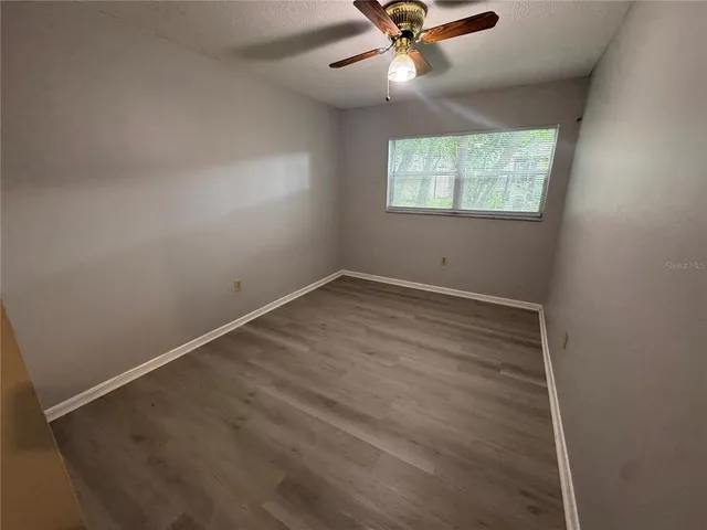 an empty room with windows and fan