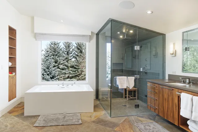 a bathroom with a tub sink shower and mirror