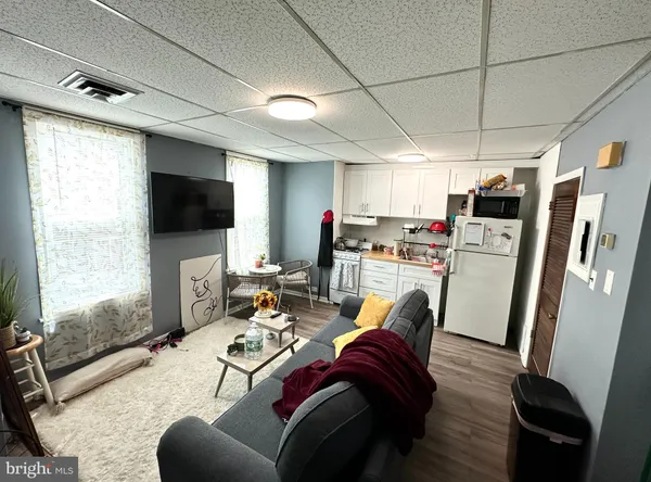 a living room with furniture a flat screen tv and a refrigerator