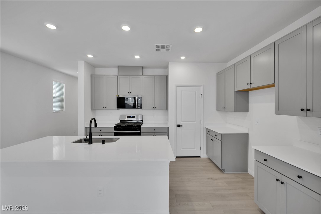 9136 Rivington Avenue Las Vegas, NV 89148 - Photo 9 of 43 Kitchen with stainless steel range, light stone counters, gray cabinets, recessed lighting, and light wood finished floors