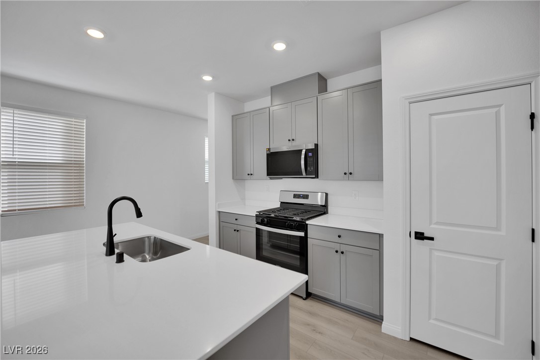 9136 Rivington Avenue Las Vegas, NV 89148 - Photo 10 of 43 Kitchen with gray cabinetry, appliances with stainless steel finishes, recessed lighting, light wood-type flooring, and light stone countertops
