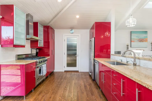 a kitchen with stainless steel appliances kitchen island granite countertop a red stove a kitchen island a refrigerator and red cabinets