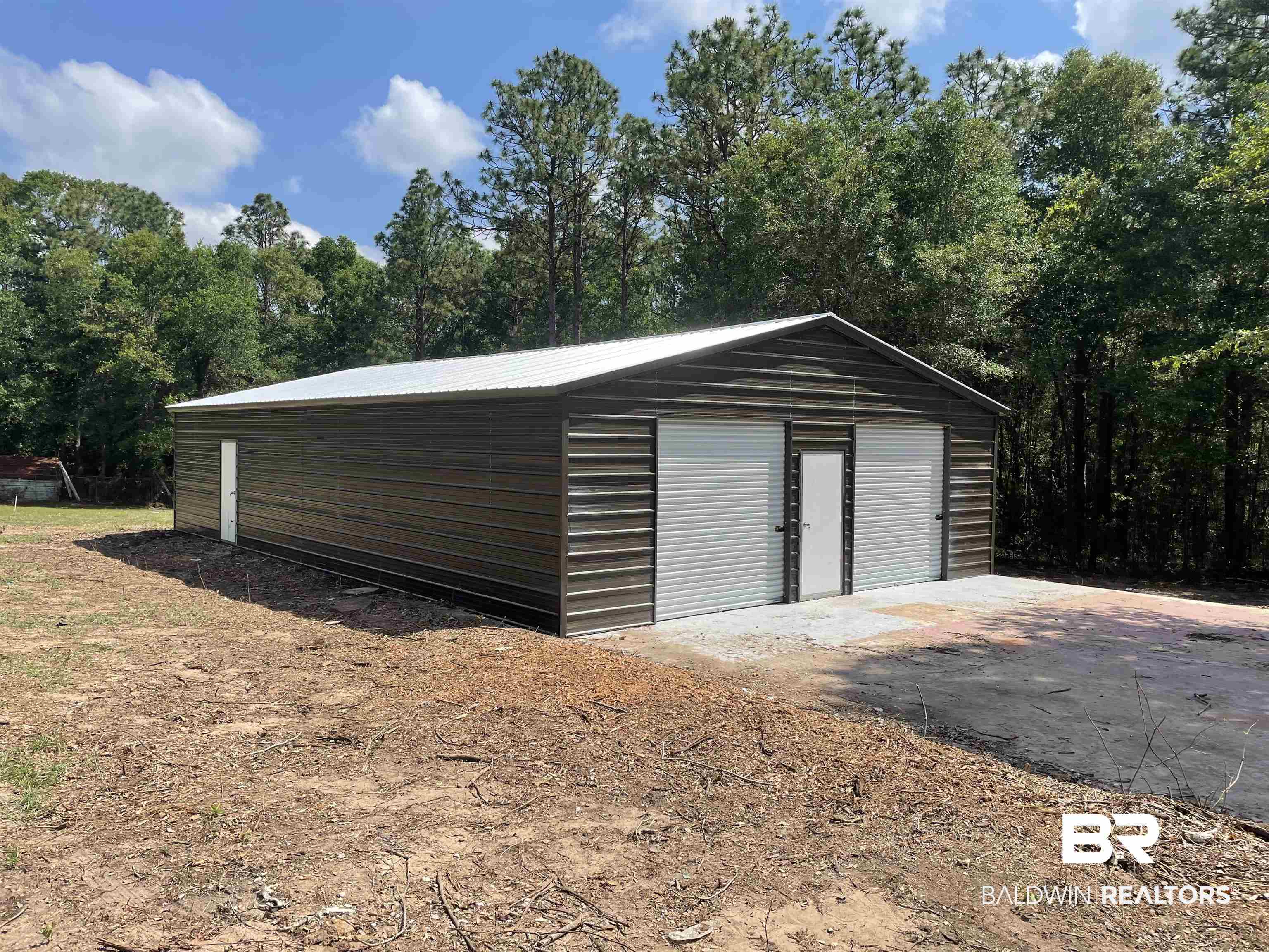 3711 Leroy Stevens Road Mobile, AL 36619 - Photo 4 of 4 Metal structure with a gable roof, two large roll-up doors, and a pedestrian door