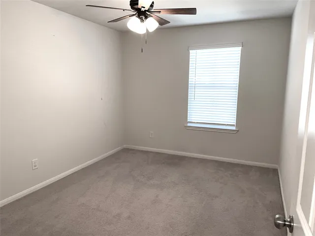 an empty room with a window and a fan