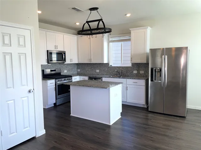 a kitchen with stainless steel appliances granite countertop a refrigerator a stove a sink and a microwave