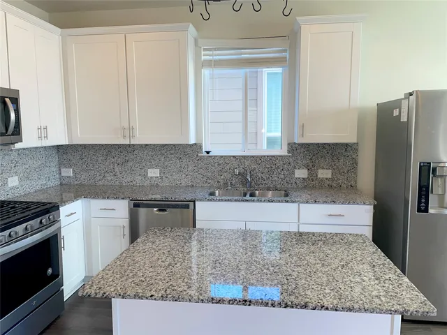 a kitchen with stainless steel appliances granite countertop a sink stove and refrigerator