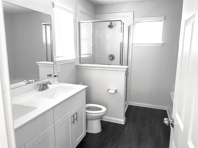 a bathroom with a sink a toilet a window and shower