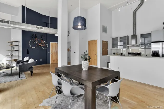 a kitchen with stainless steel appliances granite countertop a stove a refrigerator a dining table and chairs with wooden floor