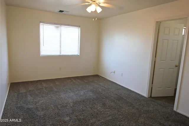 an empty room with a window and a fan