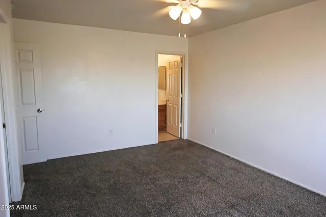 an empty room with a chandelier fan and closet