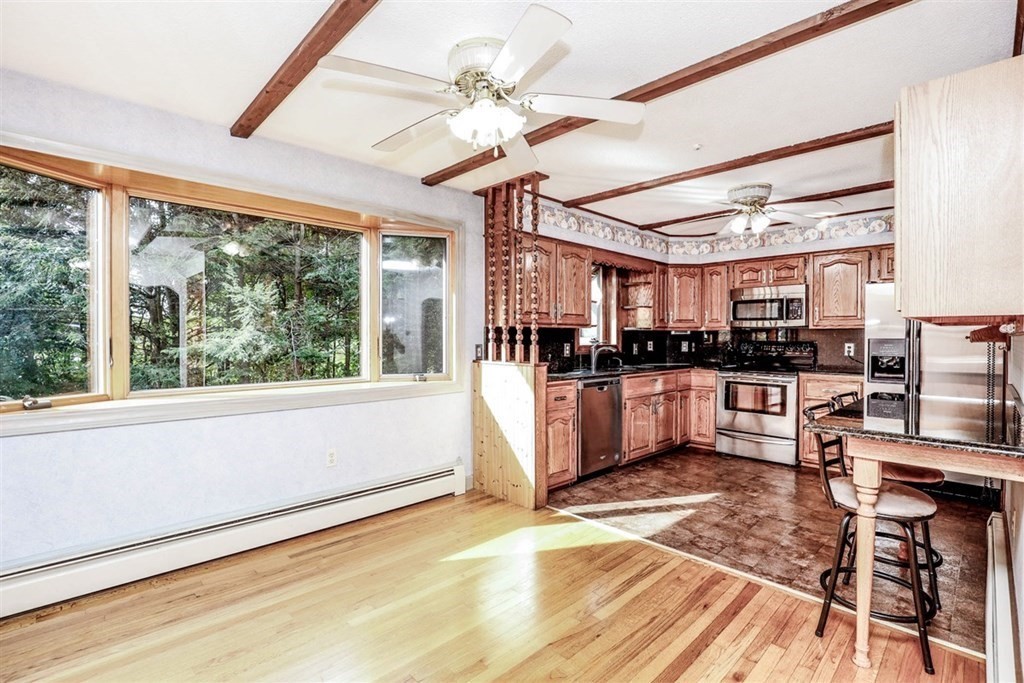 120 Chadwick Road Haverhill, MA 01835 - Photo 8 of 29 a kitchen with stainless steel appliances kitchen island granite countertop a refrigerator a sink a stove top oven a chimney and a large window with wooden floor