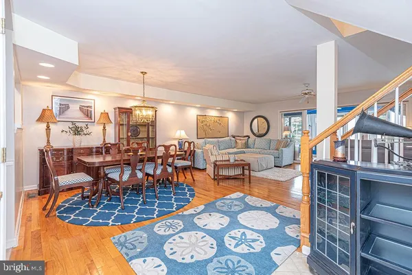 a kitchen with stainless steel appliances kitchen island granite countertop a refrigerator a sink dishwasher a stove and white cabinets with wooden floor