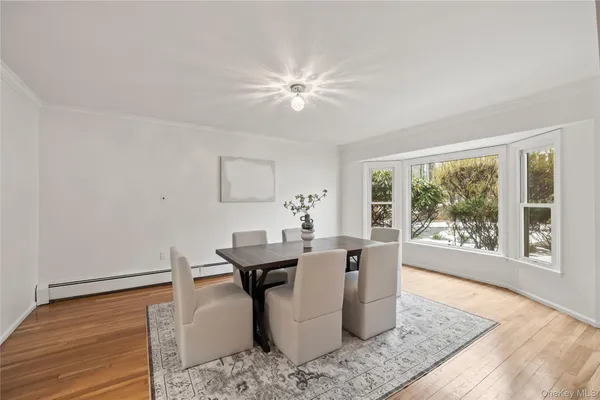 a dining room with chandelier and wooden floor