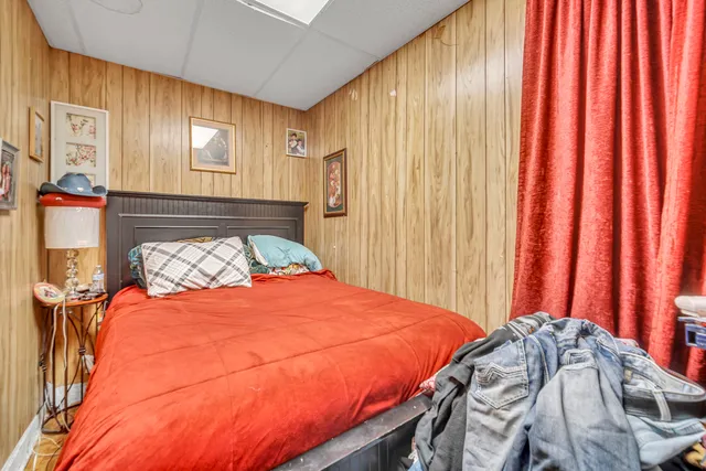 a bed sitting in a bedroom next to a window and a curtain