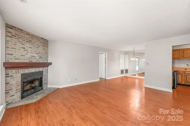 a view of empty room with wooden floor and fireplace