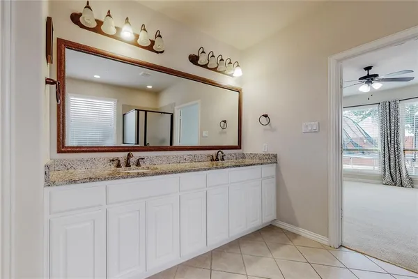 a bathroom with a granite countertop double vanity sink and a mirror