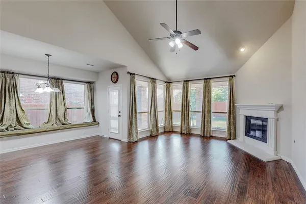 a view of an empty room with wooden floor fireplace and a window