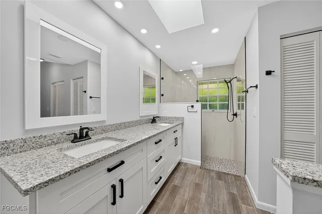 a bathroom with a granite countertop double vanity sink and a mirror