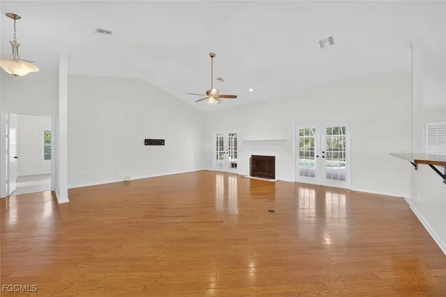 a view of an empty room with window and wooden floor