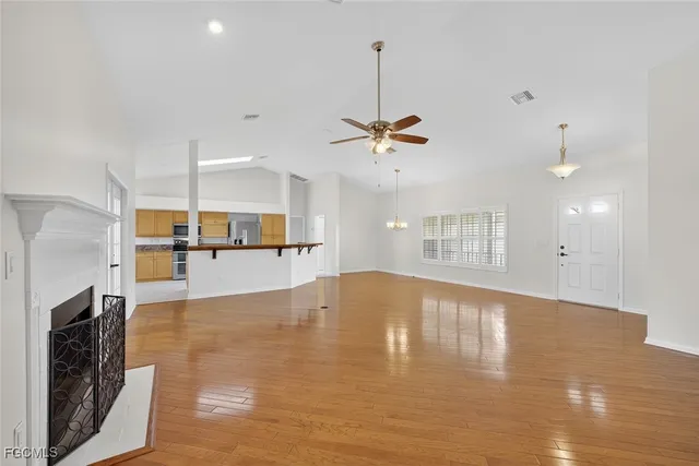 a view of an empty room with kitchen and a window