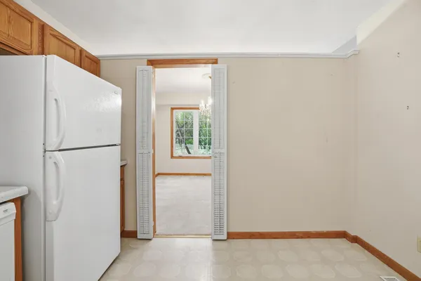 a view of storage and utility room with refrigerator and a window