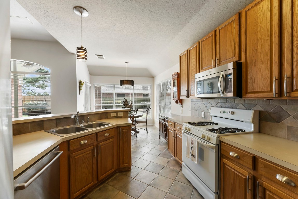 2015 Louetta Brook Court Spring, TX 77388 - Photo 9 of 28 a kitchen with stainless steel appliances granite countertop a sink stove and cabinets