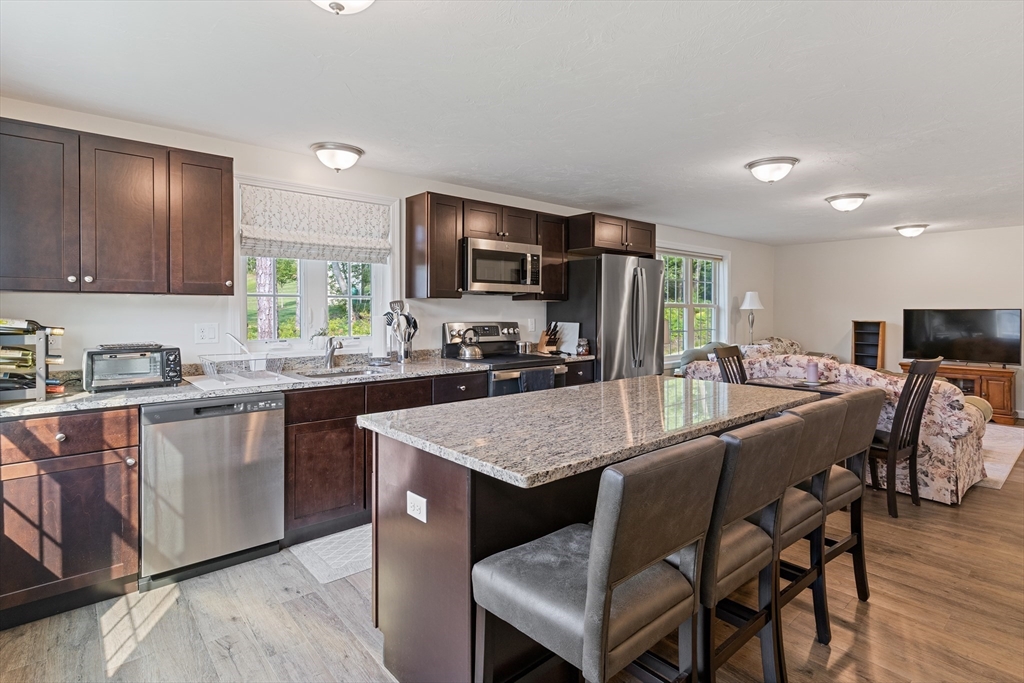 9 Tupper Hill Road, Unit 9 Plymouth, MA 02360 - Photo 11 of 30 a kitchen with stainless steel appliances granite countertop a table chairs sink refrigerator and cabinets