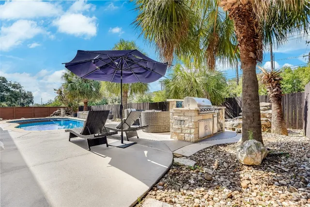a view of a patio with a table and chairs under an umbrella with palm trees