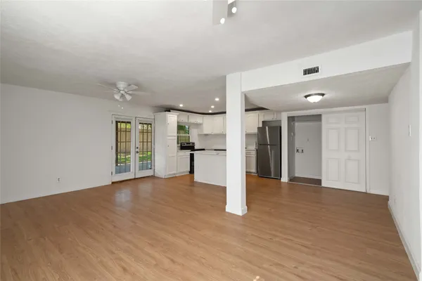 a view of an empty room with wooden floor and a window