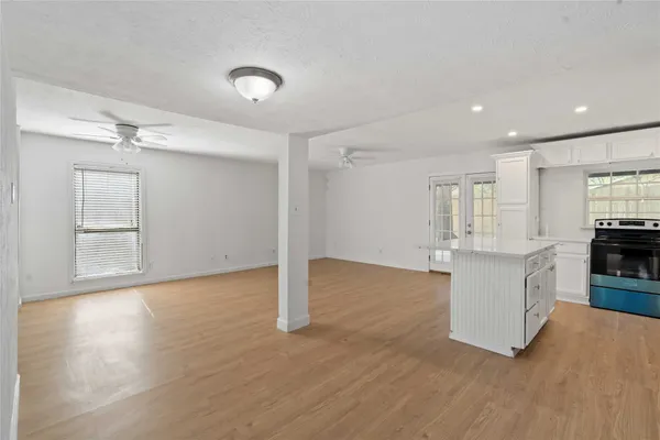 a view of kitchen and empty room with wooden floor