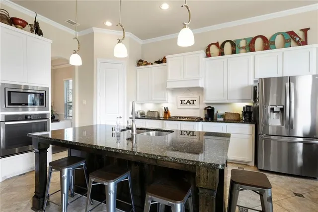 a kitchen with granite countertop a table chairs stainless steel appliances and cabinets