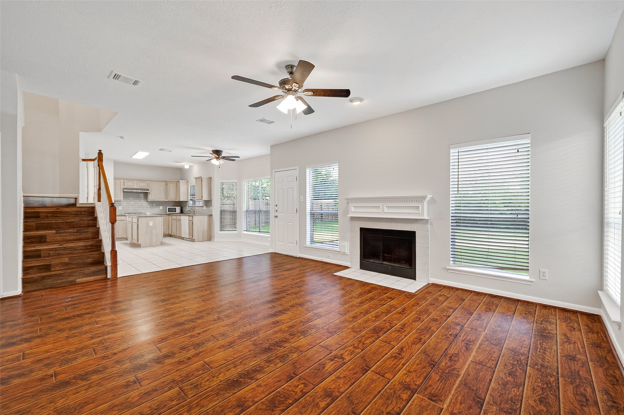 4539 Springfield Lakes Street Sugar Land, TX 77479 - Photo 14 of 34 an empty room with wooden floor a fireplace a ceiling fan and windows