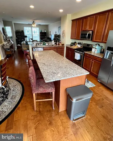 a kitchen with stainless steel appliances kitchen island granite countertop a stove a sink dishwasher and a microwave with wooden floor