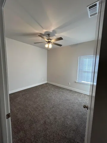 an empty room with windows and fan