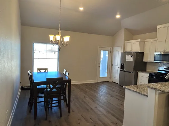a kitchen with refrigerator a sink dining table and chairs