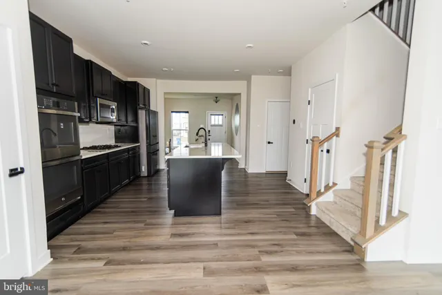 a kitchen with stainless steel appliances kitchen island granite countertop a refrigerator and a stove top oven