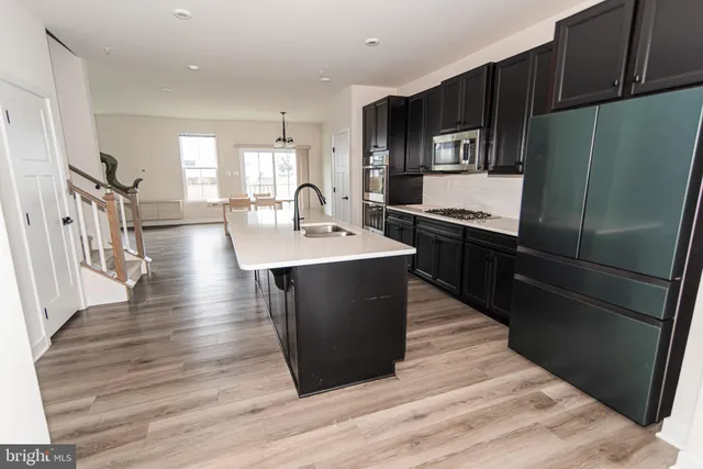 a kitchen with stainless steel appliances granite countertop a sink a stove a refrigerator and cabinets