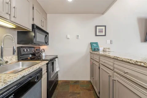 a kitchen with stainless steel appliances granite countertop a sink stove microwave and refrigerator
