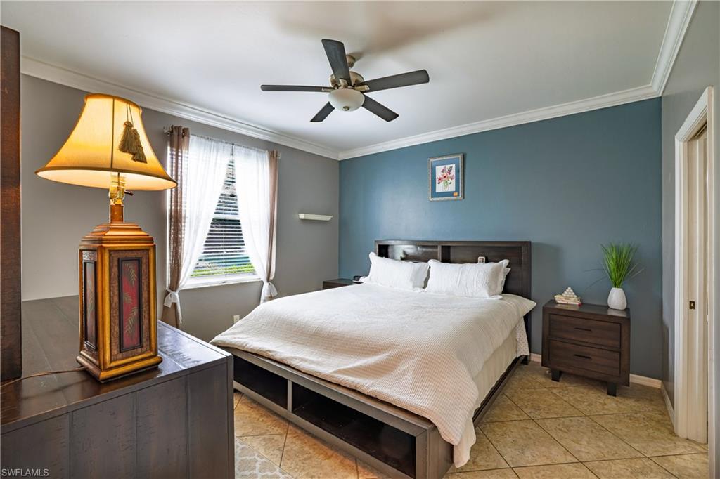 305 Robin Hood Circle, Unit 101 Naples, FL 34104 - Photo 11 of 31 a bedroom with a bed and a chandelier