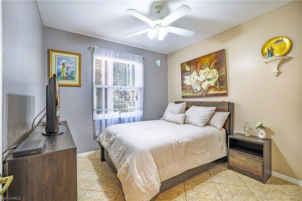 305 Robin Hood Circle, Unit 101 Naples, FL 34104 - Photo 15 of 31 a bedroom with a bed and a flat screen tv