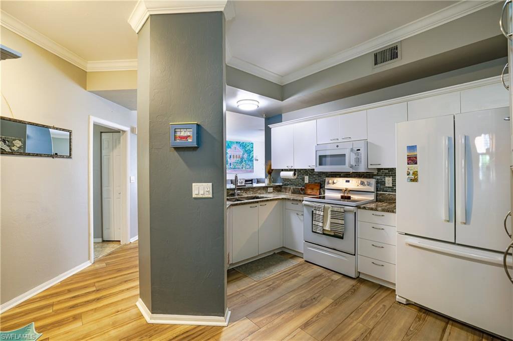 305 Robin Hood Circle, Unit 101 Naples, FL 34104 - Photo 4 of 31 a kitchen with stainless steel appliances granite countertop a refrigerator and a stove top oven