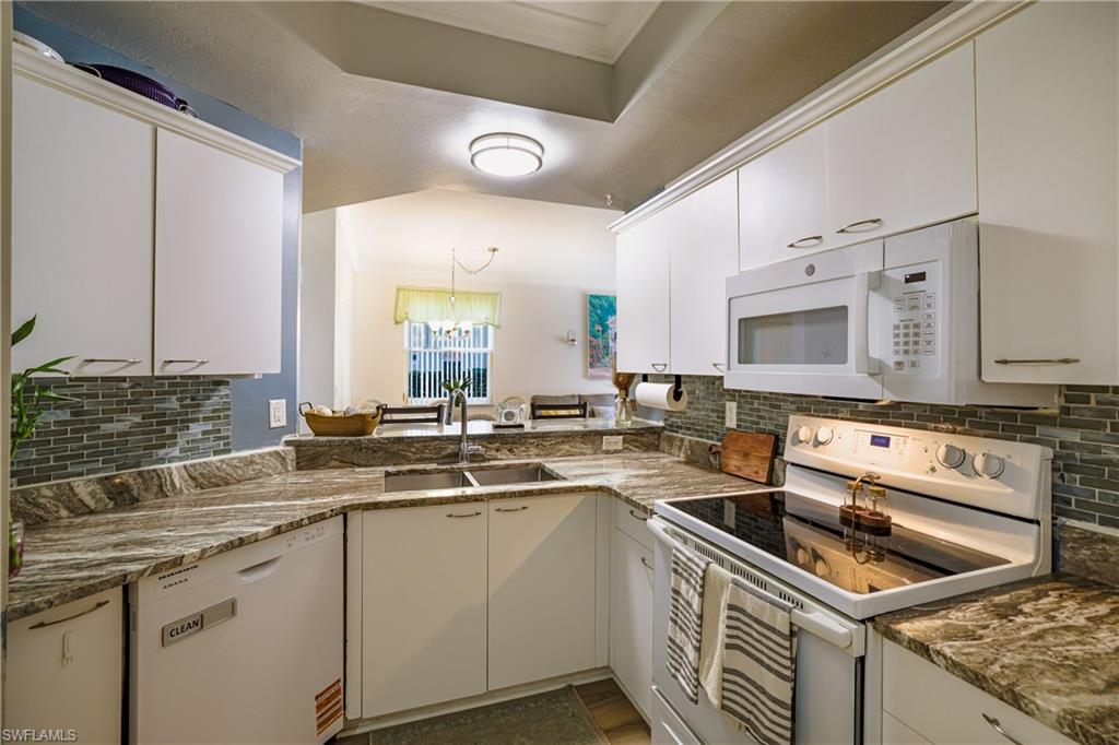 305 Robin Hood Circle, Unit 101 Naples, FL 34104 - Photo 7 of 31 a kitchen that has a sink and a stove