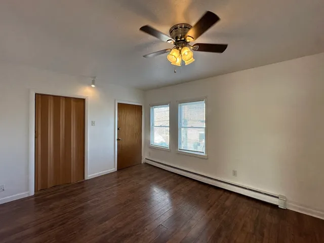 a view of an empty room with a window and wooden floor